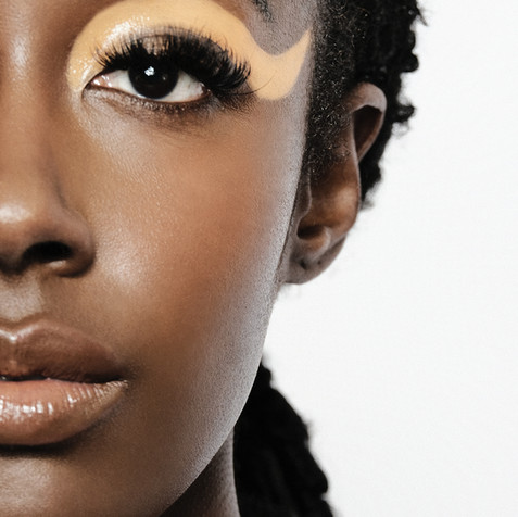 Black model smiling with orange eye makeup 