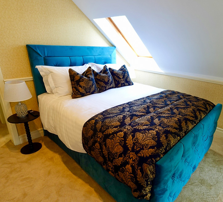 Bedroom with a teal bed, patterned bedding, and a skylight