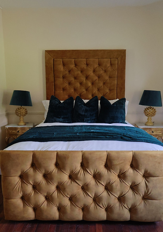 Elegant bedroom with gold tufted bed and ornate mirror