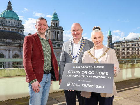 Three people standing with a board advertising the event
