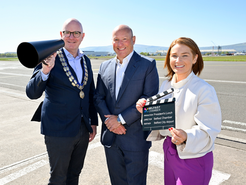 Three people with film props standing on an airport runway