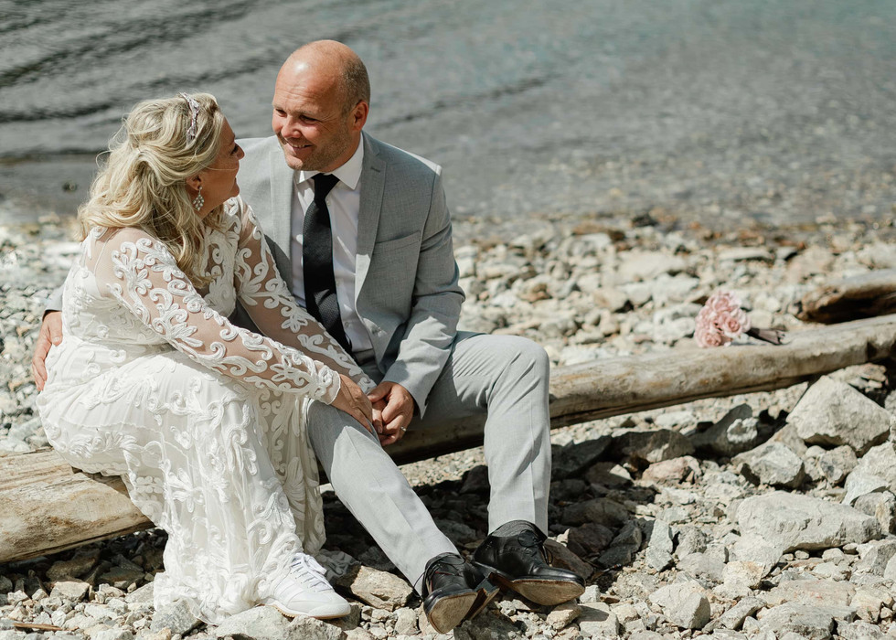 A newlywed couple spending time together on a rocky beach on their elopement day