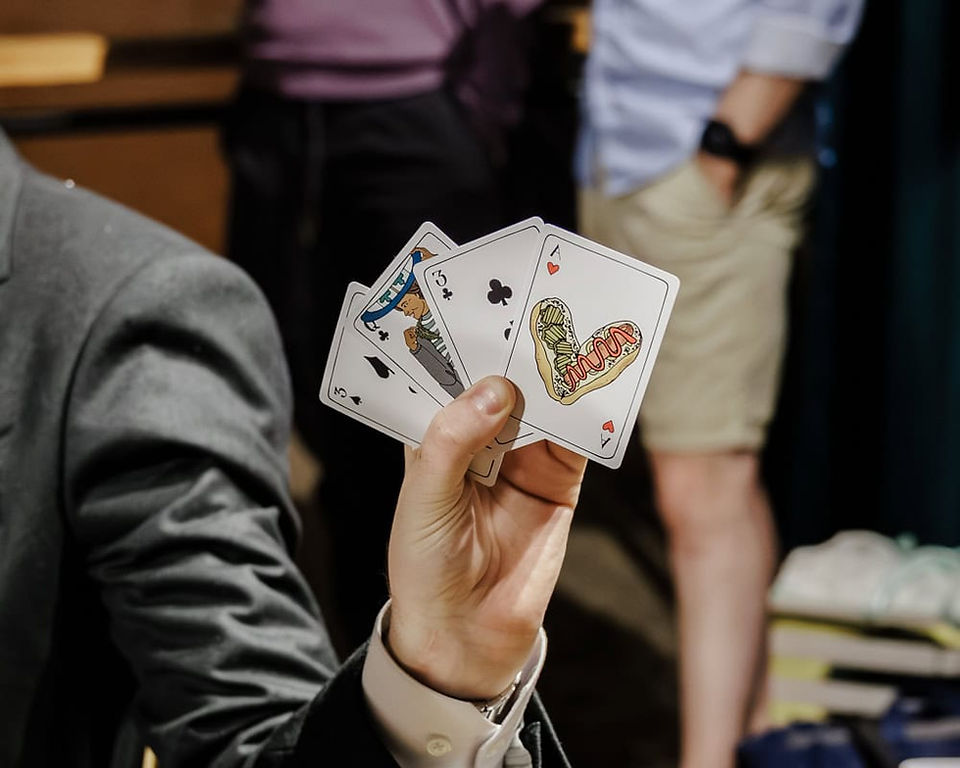 A close up of a groom holding up his hand of cards during the first crib game.