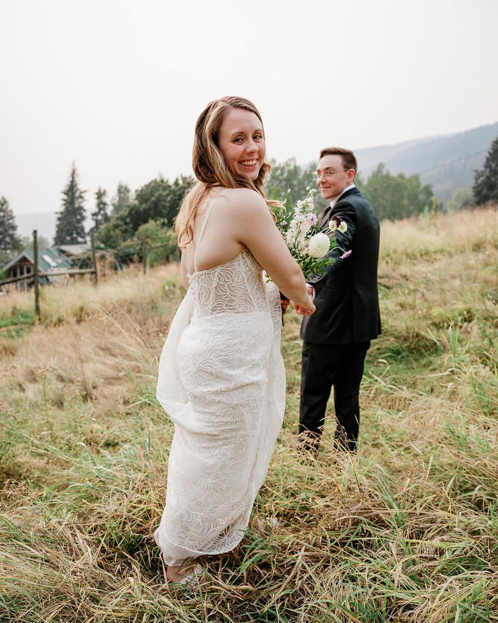 A couple walking in a field on their wedding day