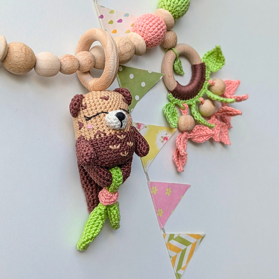 Thumbnail: Crocheted otter rattle and wooden ring with crocheted botanical elements for a stroller chain by ColoredYarn