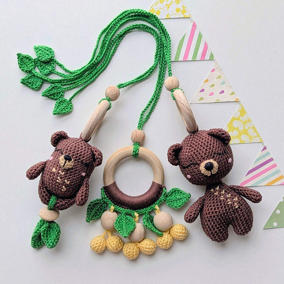 Thumbnail: Three crocheted hanging toys for a baby gym featuring a wooden ring, a rattle, and a stuffed bear
