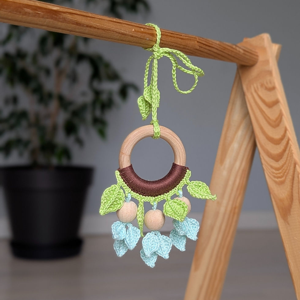 Thumbnail: Crocheted hanging toy with a wooden ring with botanical motifs on a wooden baby gym frame