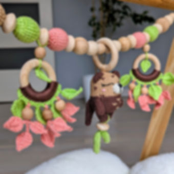 Full view of handmade stroller chain sensory toy with otter rattle and wooden rings with crochet leaves.