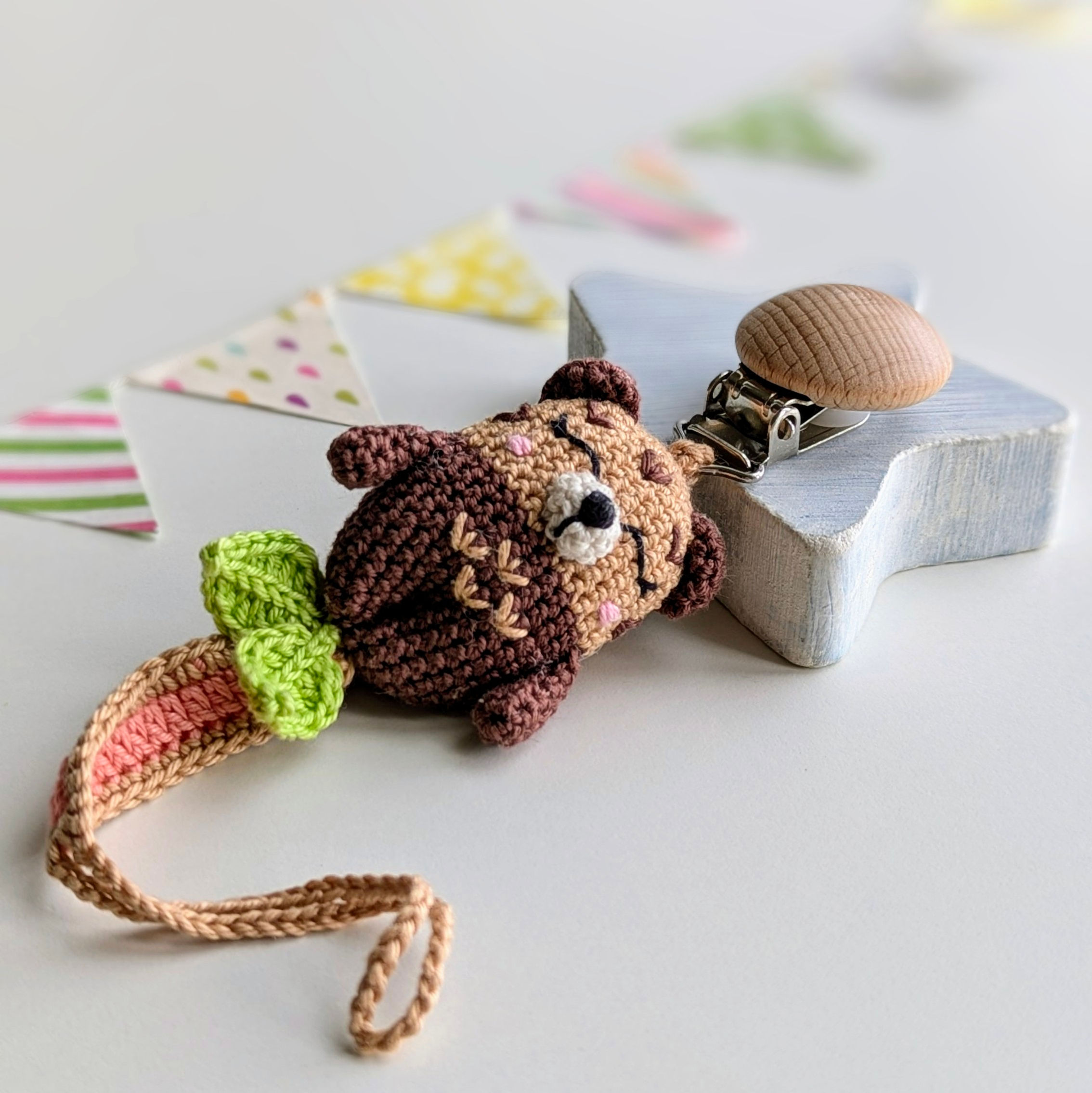 Handcrafted otter pacifier clip in earthy brown, caramel, coral and green tones
