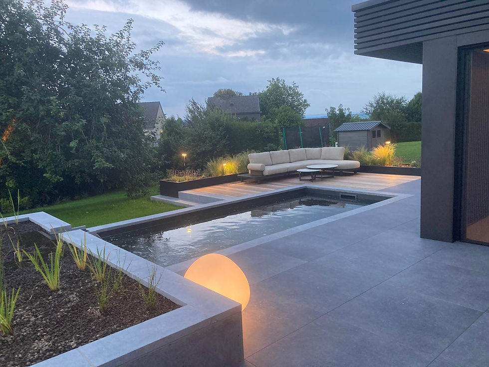 Baignade naturelle avec habillage en pierre bleue, entourée de terrasses en bois exotiques et grès cérame
