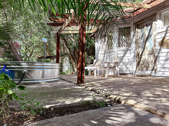 הבקתה הזוגית של סקיי מטיילים מבחוץ הכוללת פינת ישיבה ושכשוכית מים וצמחיה עשירה