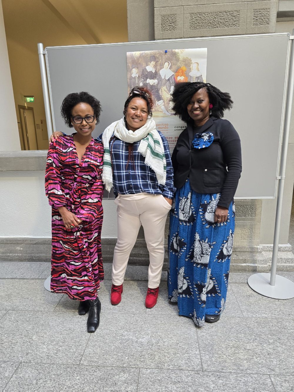 Three women standing in front of the conference poster