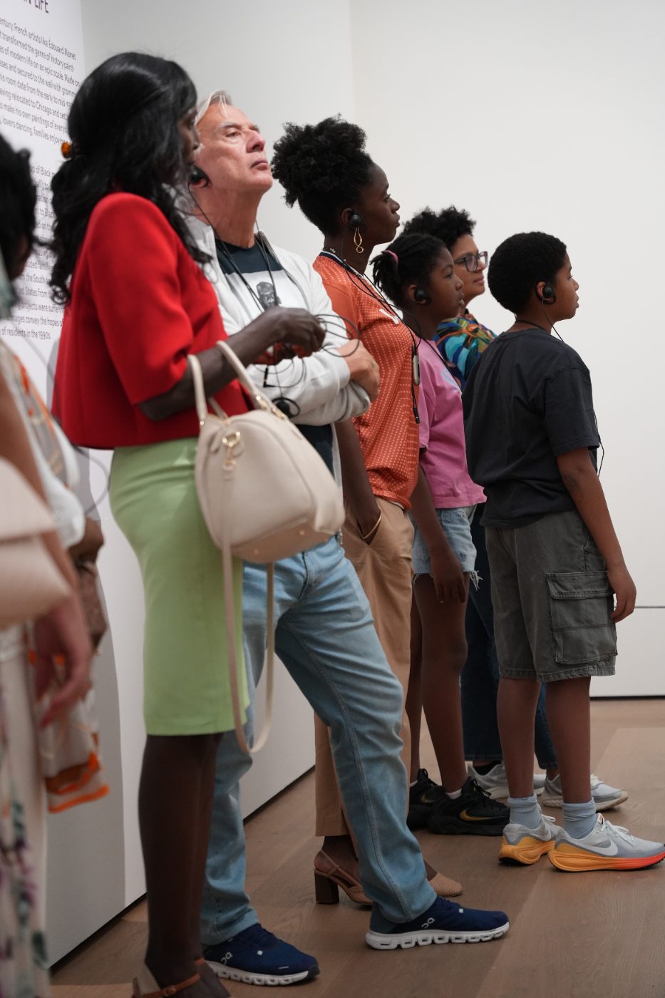 Guests of all ages standing in a row, looking at a painting
