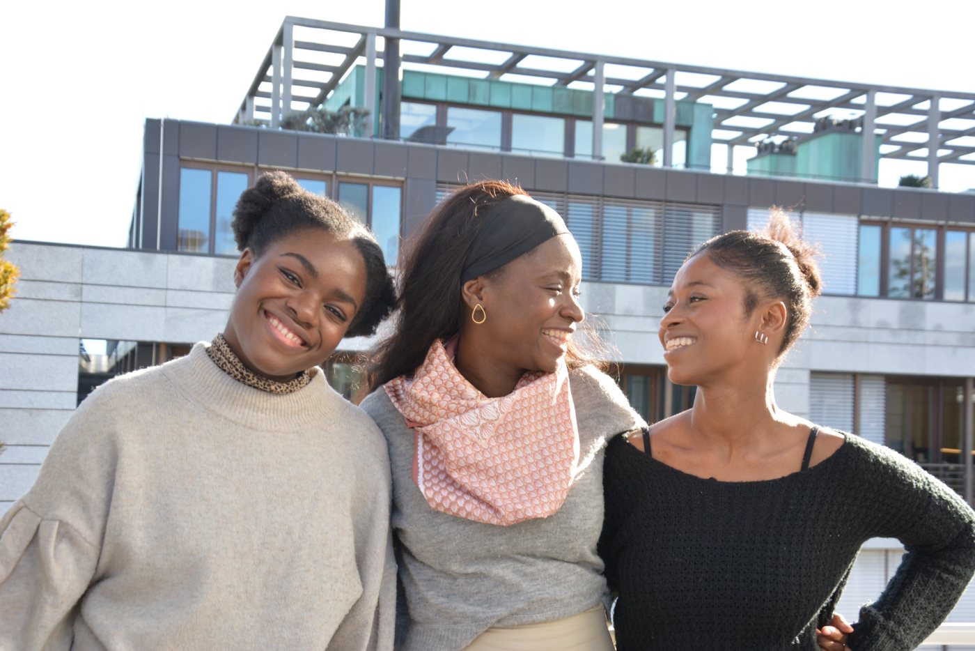 Three women laughing together on a terrace
