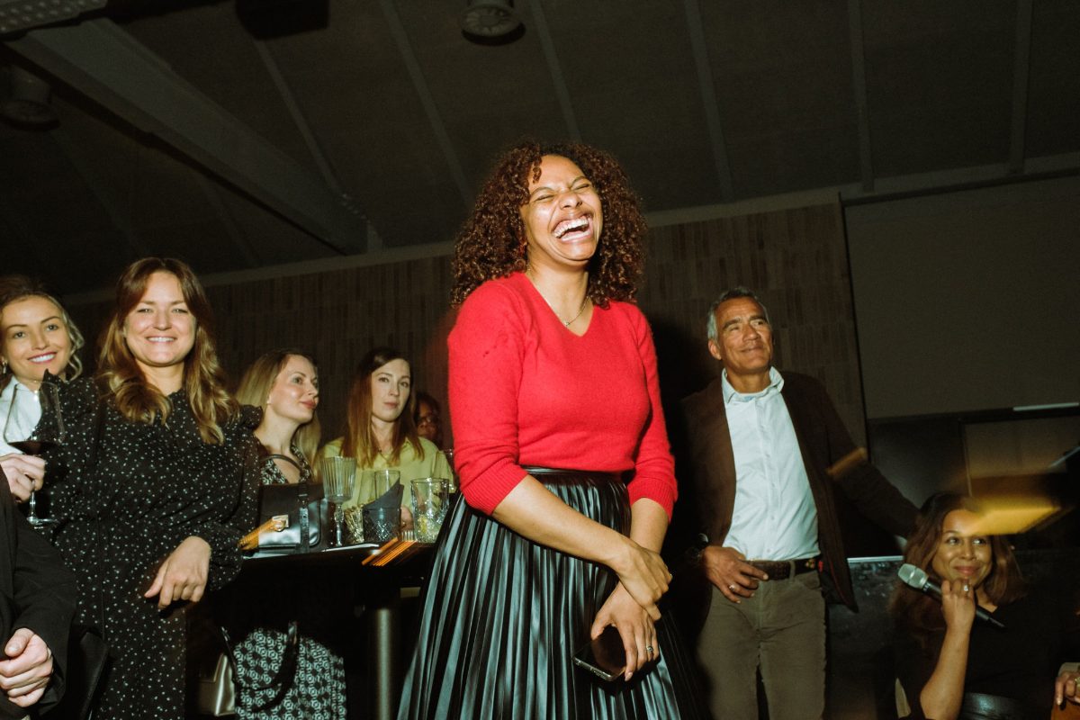 A guest in a red jumper laughing among other guests