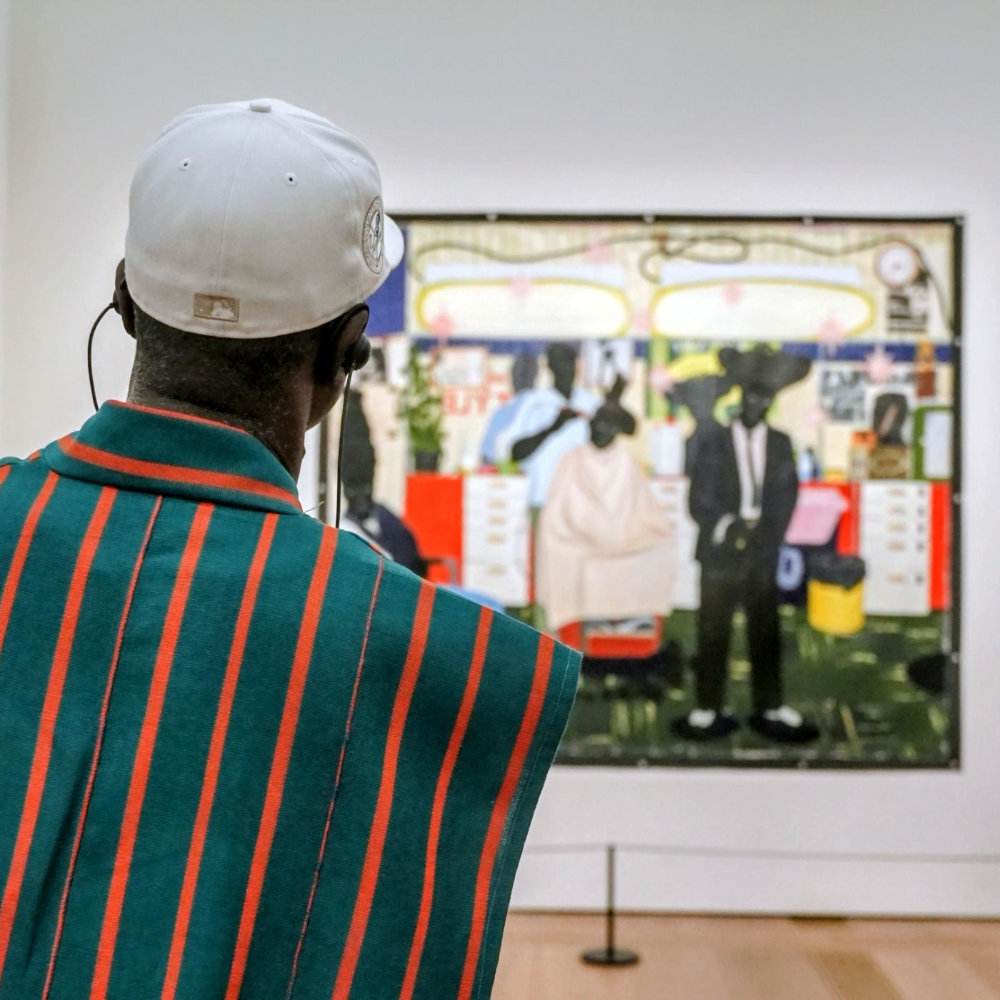 A guest in a white cap in front of the barbershop painting