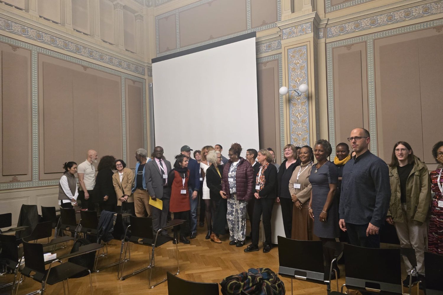 A large group of conference participants standing in front of a projection screen