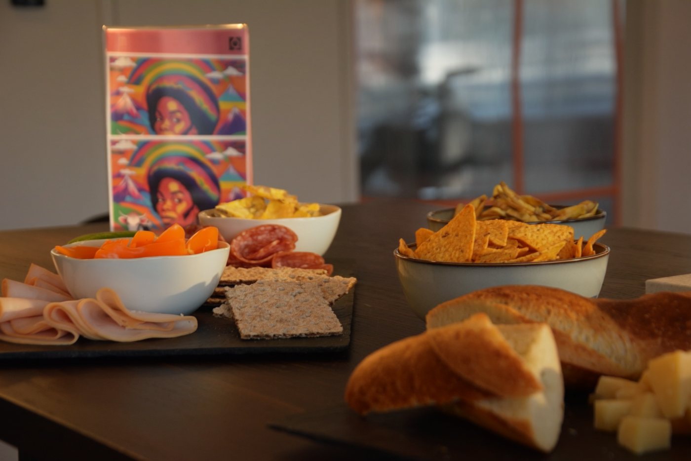 A table with bread, crisps and dips, and an illustrated card