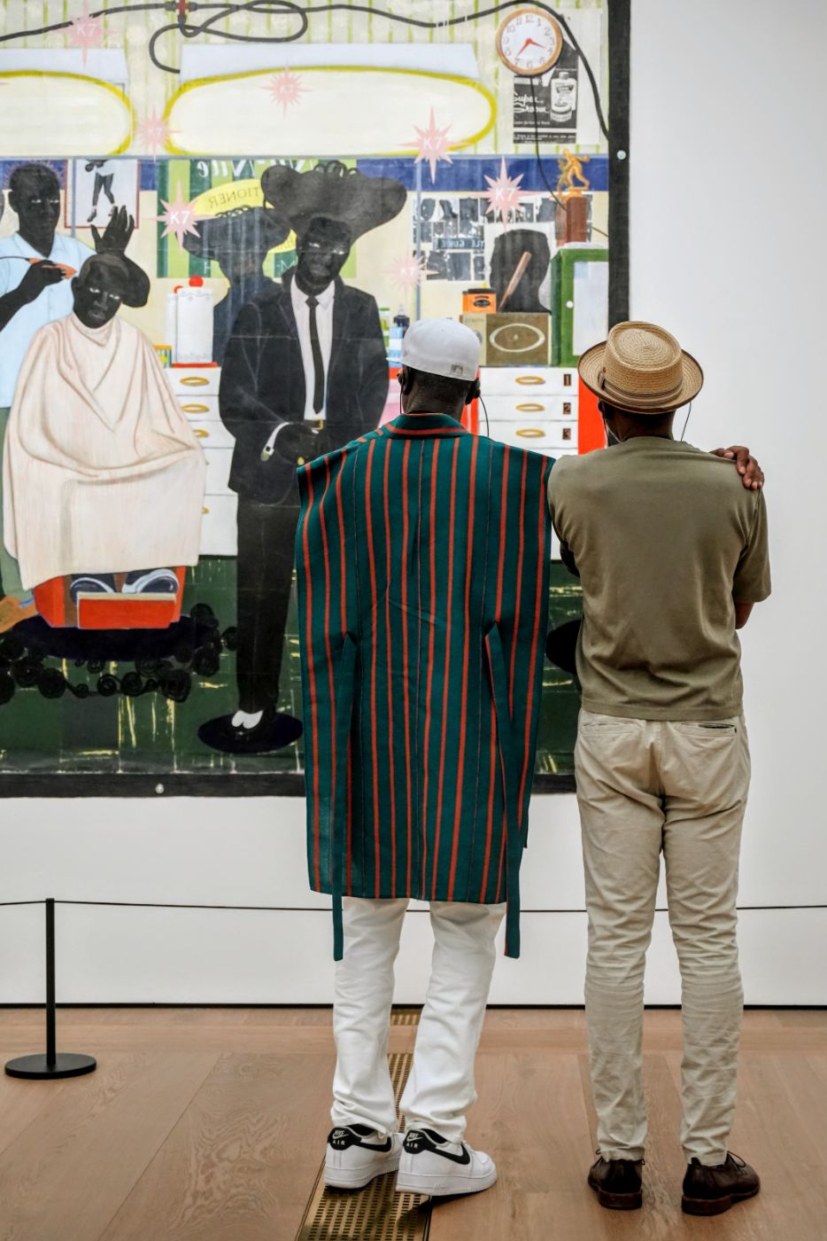 Two guests side by side in front of the barbershop painting