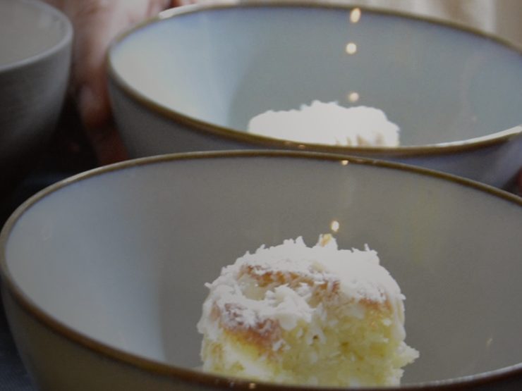 A small cake topped with grated coconut, served in a ceramic bowl