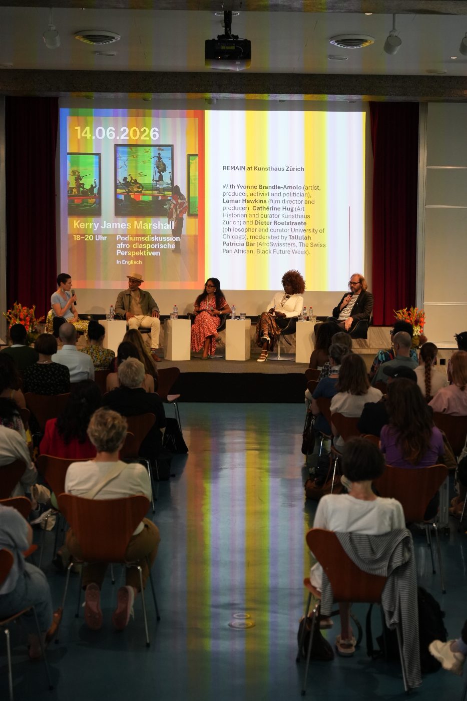 The audience in the hall, seen from the back, facing the panel