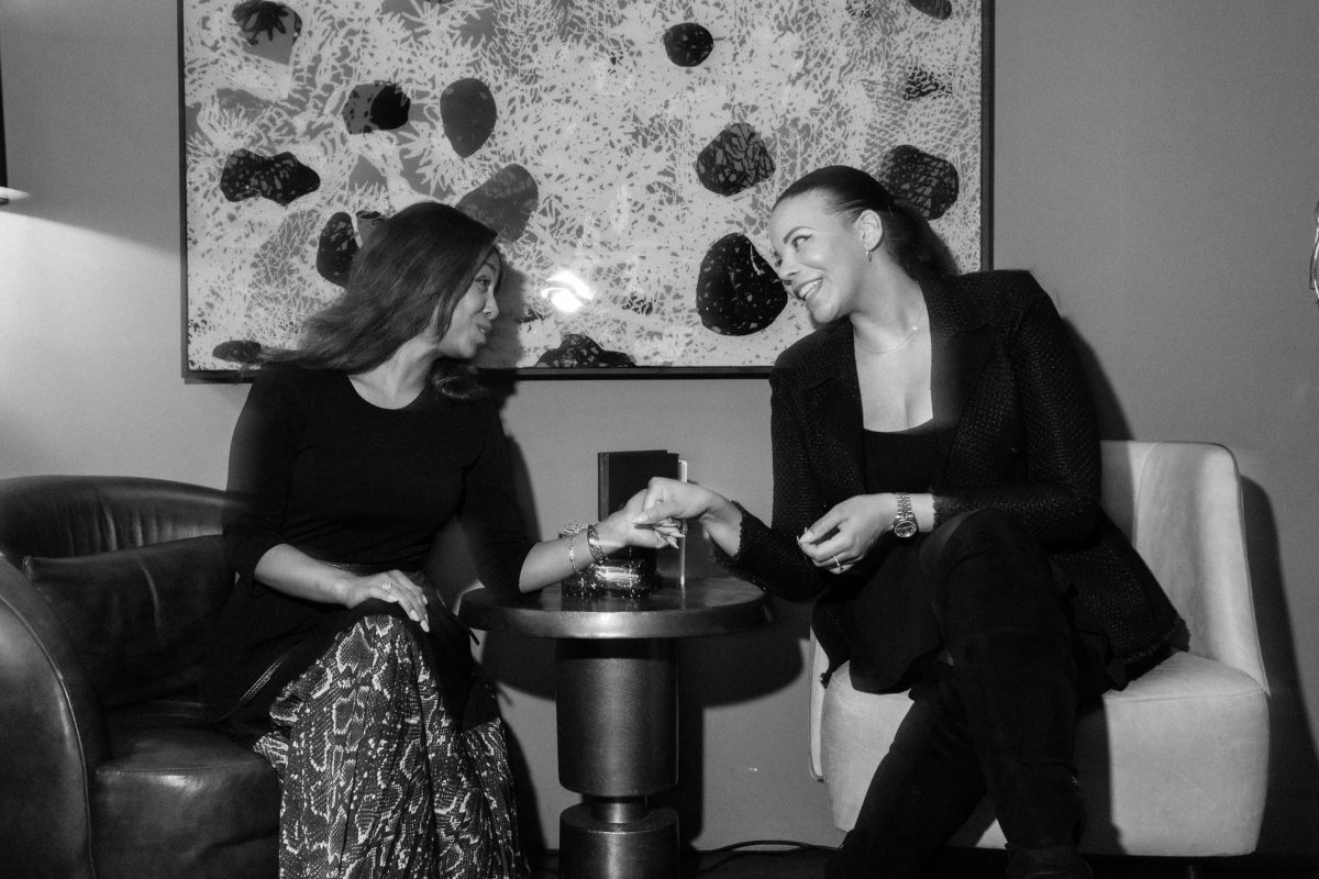Two guests holding hands and laughing, in black and white