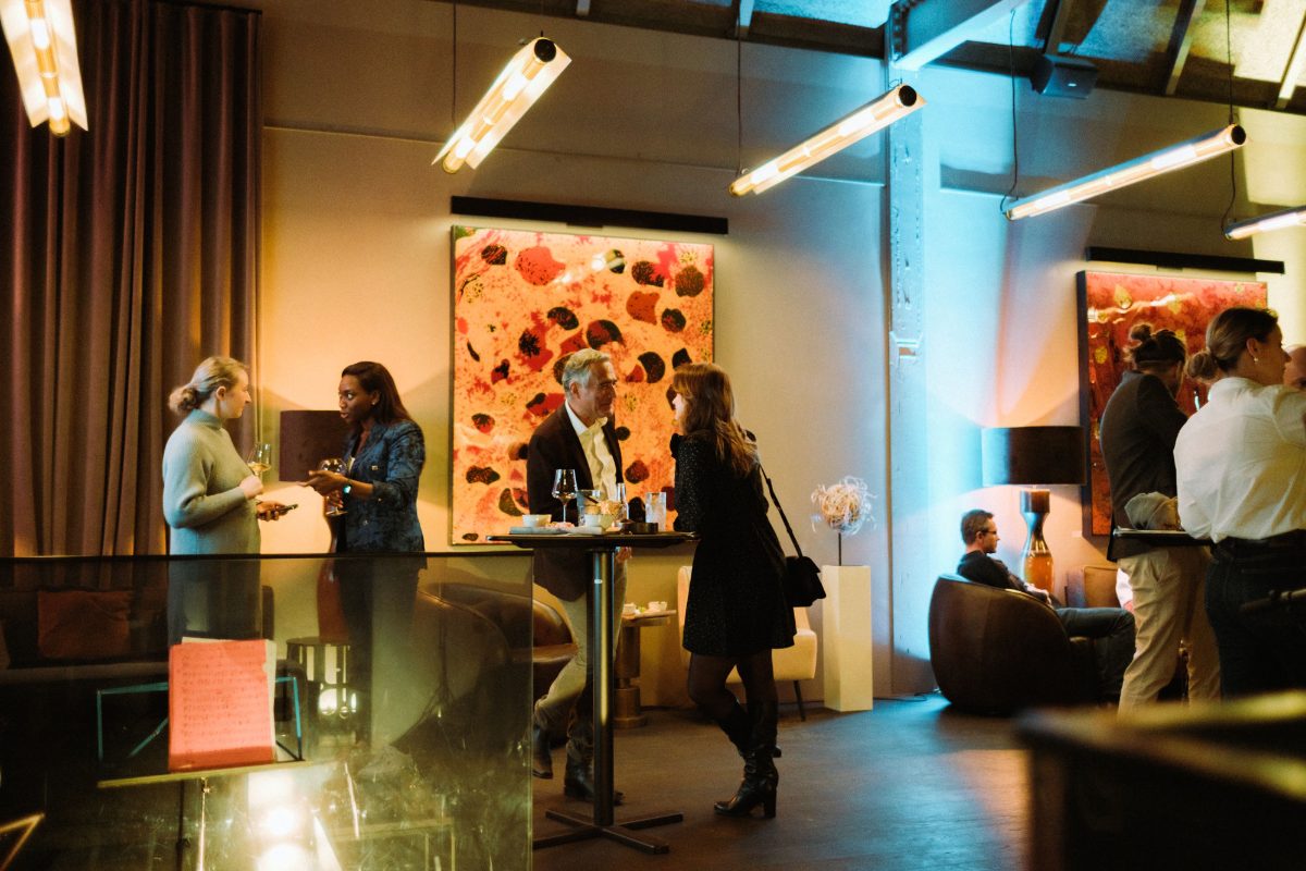 Guests talking in a room hung with large paintings