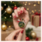 Motorsport Holiday Wine Charm. Close-up of gold-plated, green enamel, gear-themed charm with Santa stocking and candy cane ac