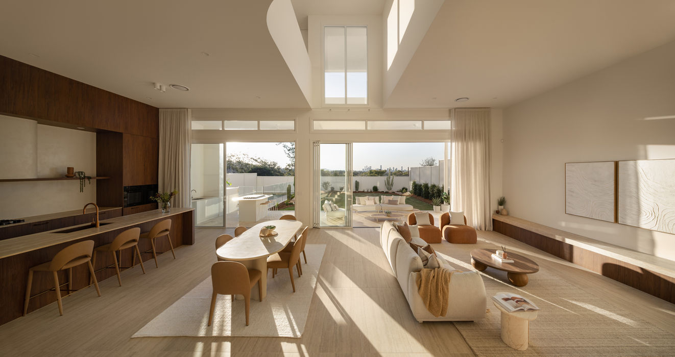 The full width of Sierra's living level in one view - kitchen, dining and lounge sharing vein-cut tiled floors and an elevated outlook over Holland Park West. The plan is deliberately uninterrupted, with no wall between the three zones. Built by Sabdia, Brisbane.