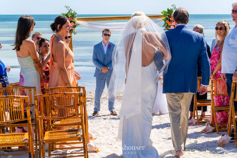 A bride walking towards her groom for their destination beach wedding