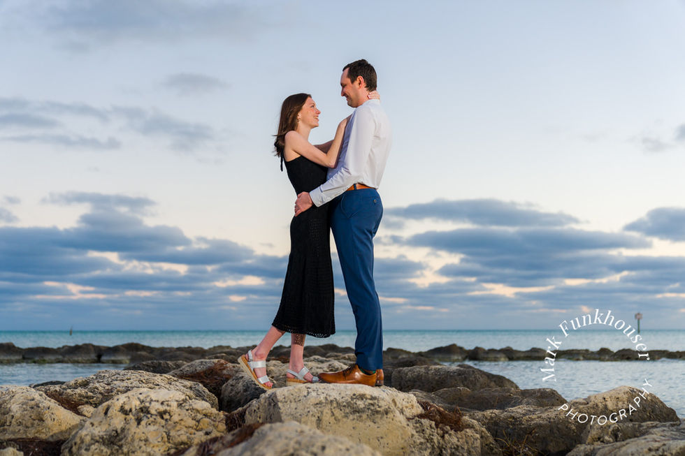A man and woman are holding each other while having their photo taken by a Key West photographer for their engagement