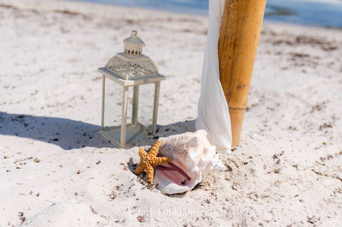 A conch shell and lantern are on the beach for a Florida Keys destination wedding