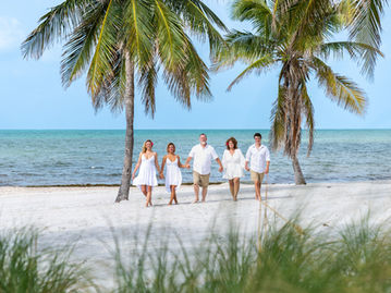 A family is holding hands and walking on the beach during a mini session photoshoot in Key West