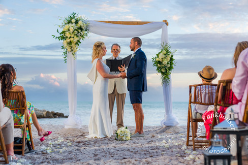 A man and woman getting married on the beach in Key West with friends and family watching