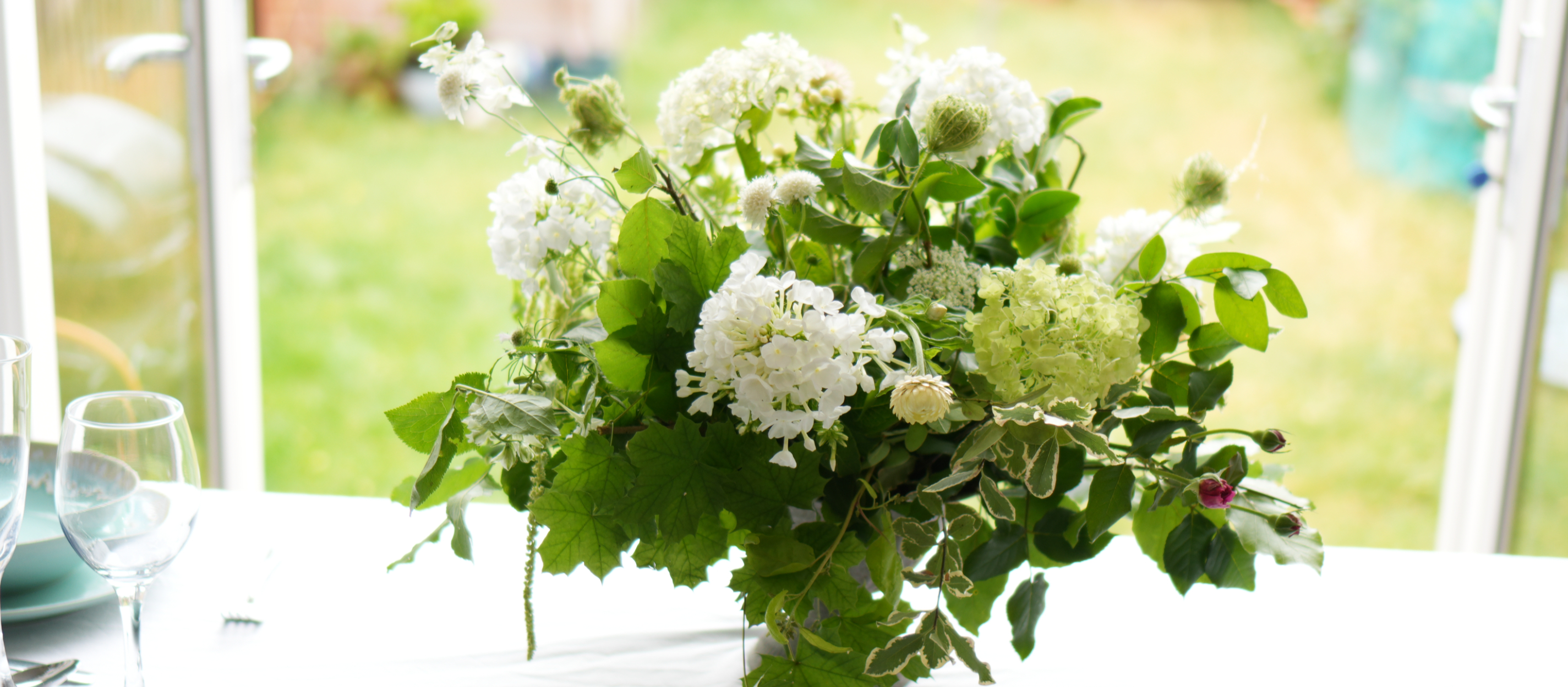 A classic wedding floral arrangement with white flowers in a white urn