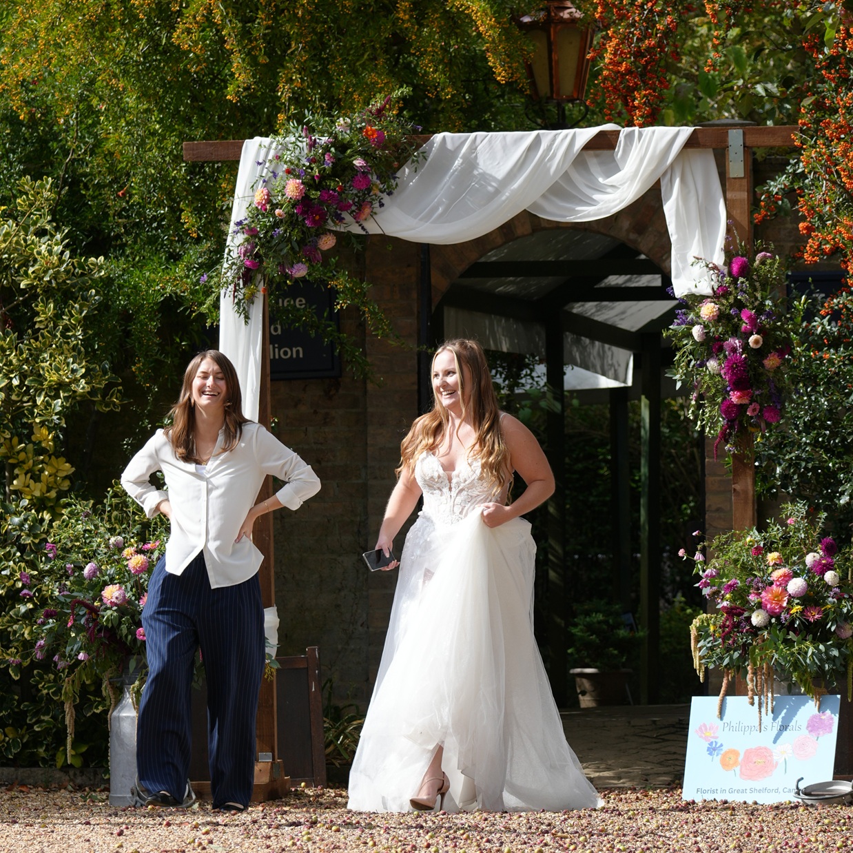 A beautifully decorated wooden wedding arch and a smiling bride