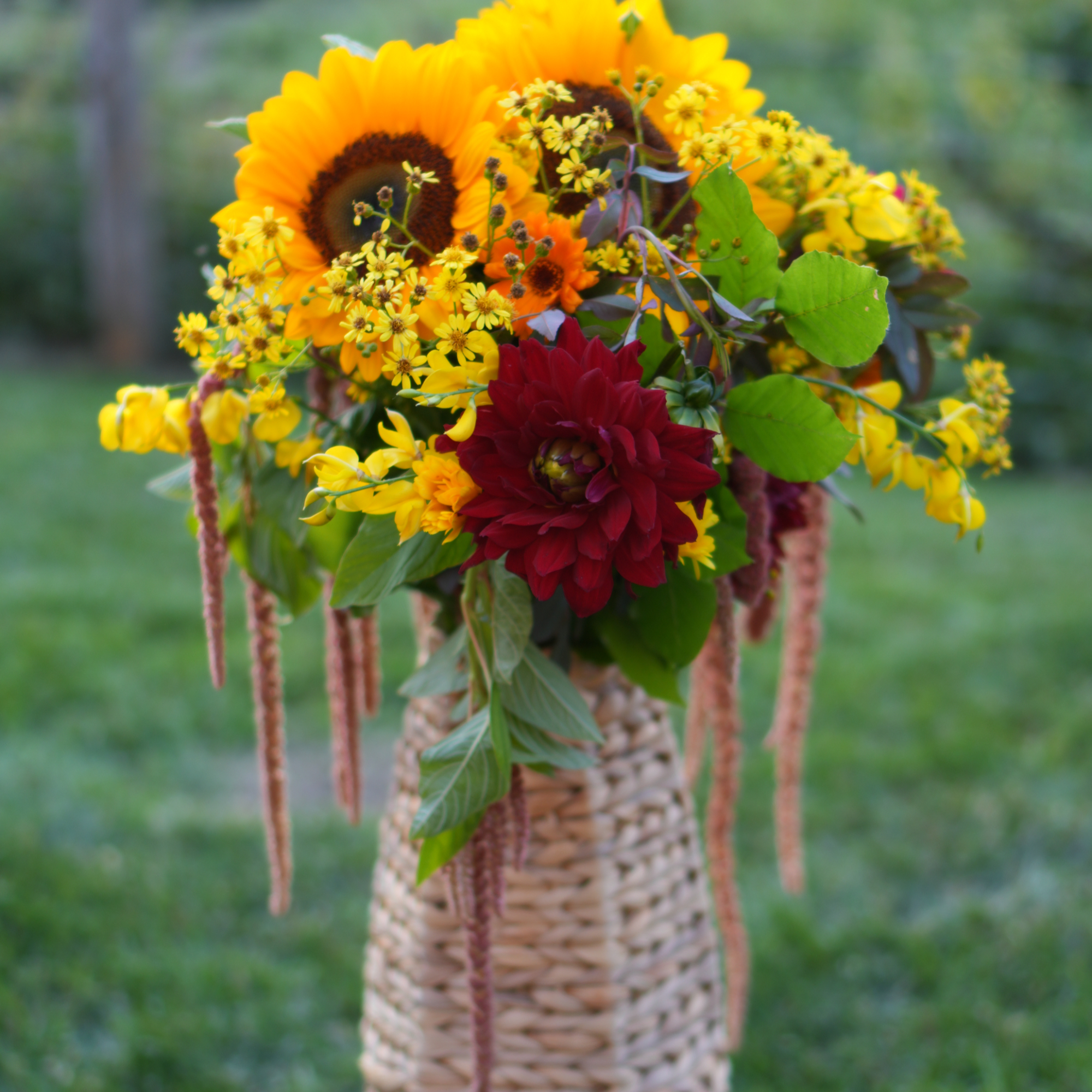A cheerful wedding arrangement in a basket featuring a large sunflower