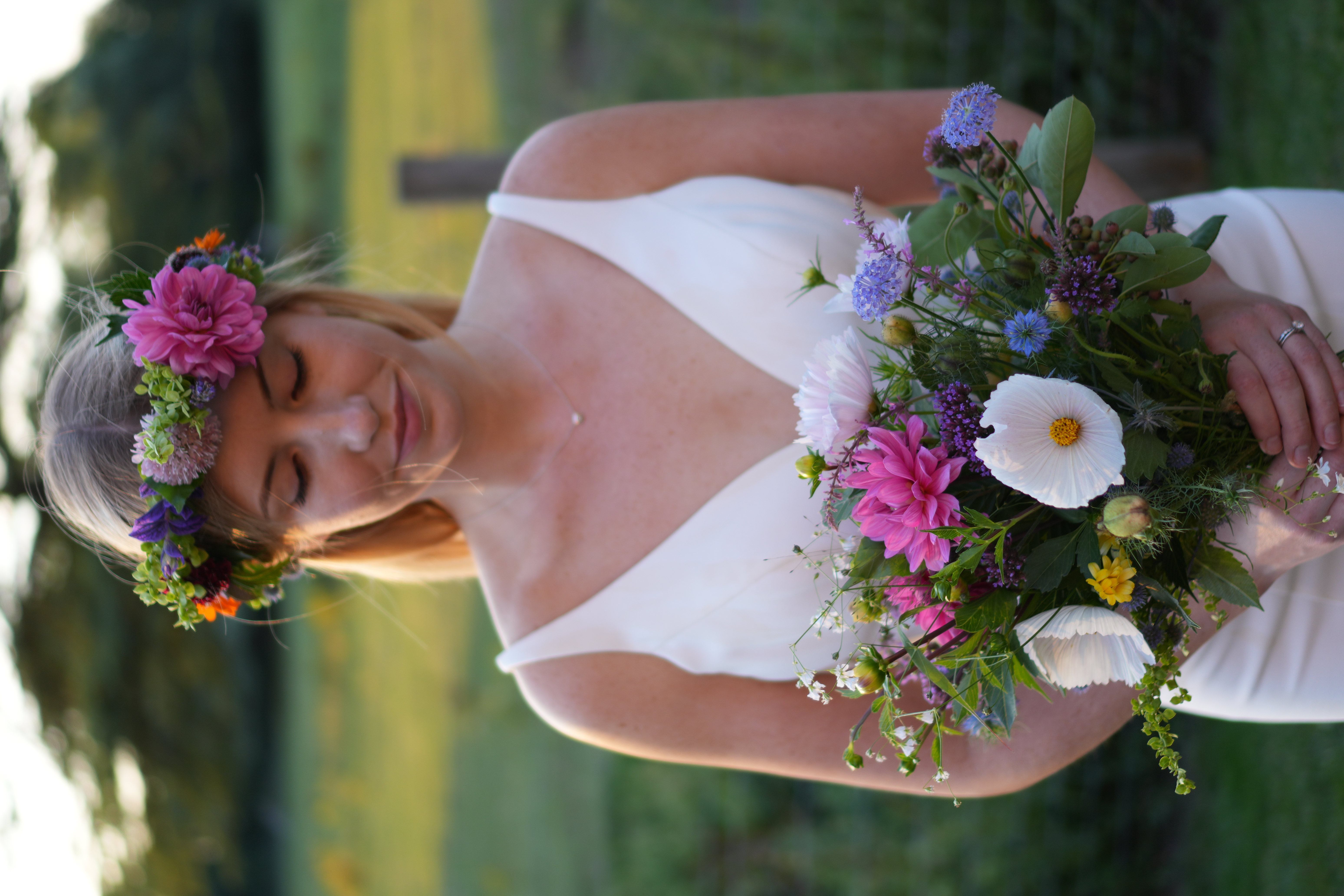 Woman facing forward, wearing a flower crown and holding a multicolour bouquet