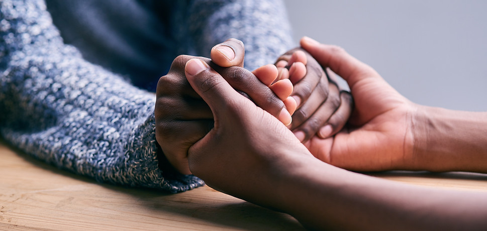 Photo of one person holding anothere person's hands in a caring, empathetic way.