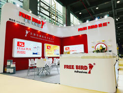 Фотография стенда компании FREE BIRD Adhesives на международной выставке, где представлены различные виды горячего клея и клеевых технологий. На заднем плане видно экспозицию и посетителей, сотрудники компании демонстрируют продукцию клиентам.