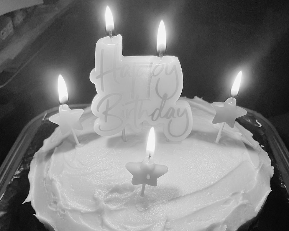 Lit birthday cake with star-shaped candles and a ‘happy birthday’ candle, filtered in soft tones, reflecting the bittersweet emotions many adoptees experience on birthdays.