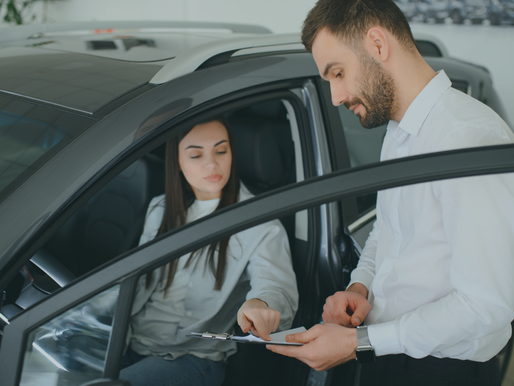 Person in new car and vehicle purchase documents, illustrating eligibility for the federal auto loan interest tax deduction.