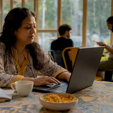 Woman researching desi snack online store on laptop