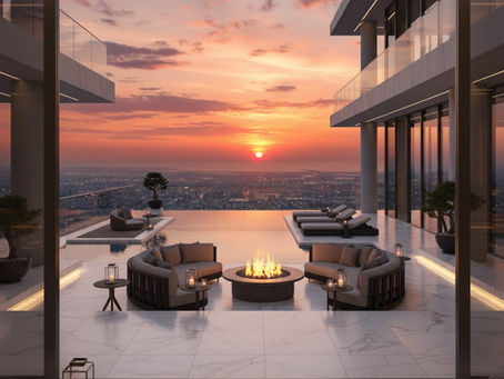 Uma varanda moderna e luxuosa num prédio, com uma piscina infinita que se estende até ao horizonte, onde o sol se põe num céu laranja vibrante. Há uma lareira no centro, rodeada por dois sofás curvos e cinzentos, com pequenas mesas laterais. Espreguiçadeiras alinham-se na piscina. A varanda tem um chão de mármore branco e está rodeado por grandes janelas de vidro que refletem o pôr-do-sol. A paisagem urbana, com edifícios e luzes, pode ser vista à distância.