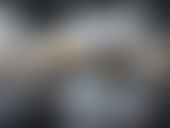 A modern office desk with an ergonomic chair in the foreground, overlaid with three digital images within futuristic neon frames. The left image shows a photorealistic interior of a luxurious living room with a city view. The central image, simulating a video with a small play symbol, displays a 3D animation of a residential development with a pool and palm trees at sunset. The right image features an interactive virtual tour interface of a modern interior, with customization options and overlaid data. This visual composition compares graphic rendering, animation, and virtual tours for architectural and real estate projects.