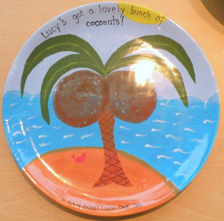 Boob prints on a plate, the prints have been turned into coconuts on a tree and there is the wording 'Lucy's got a lovely bunch of coconuts!' above the tree