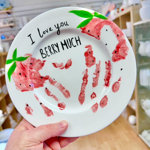 Rimmed plate with a strawberry handprint design.