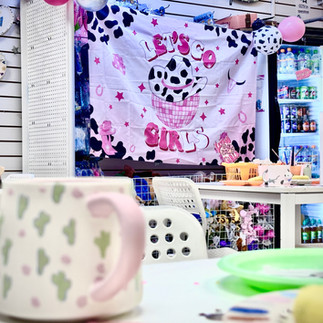 A shot of our tudio with our Rodeo theme banner in the background and a mug painted with cactus