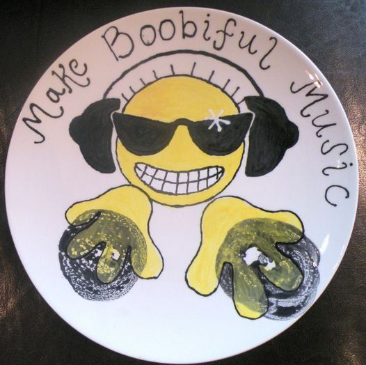 A Plate with boob prints on, the prints have been turned into discs with a DJ playing them, the words 'Make Boobiful Music' is painted above.