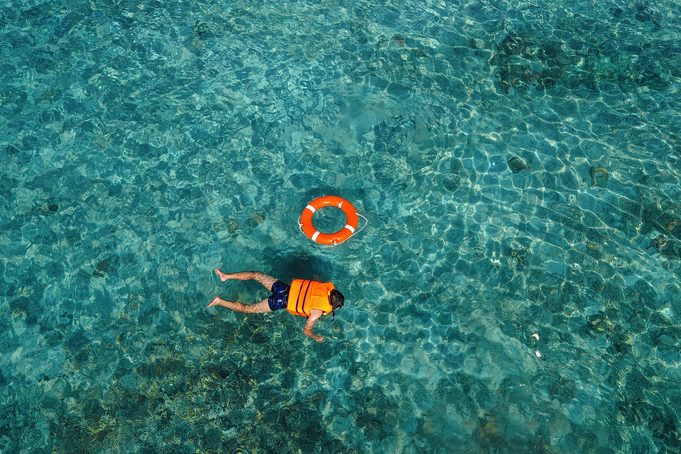Person with life jacket on in the middle of the ocean